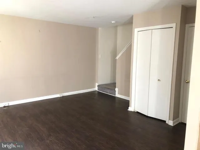 a view of an empty room with wooden floor and closet