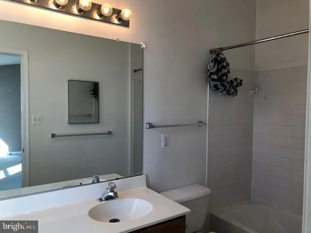 a bathroom with a sink and mirror with toilet