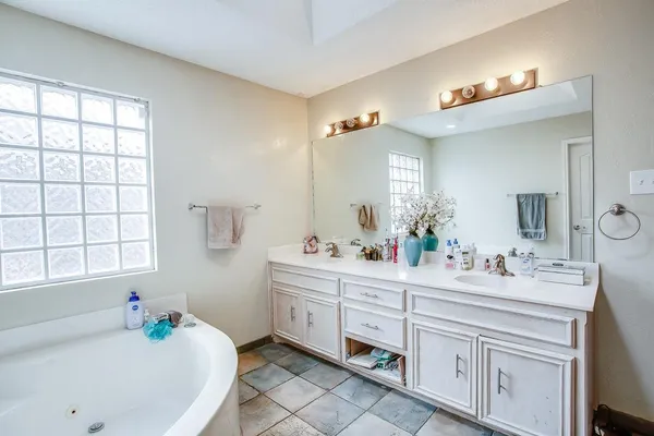 a bathroom with a sink vanity tub and a mirror