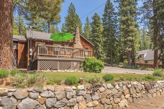 a view of a brick house with a small yard and large trees