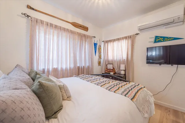 a bedroom with a bed television and a window