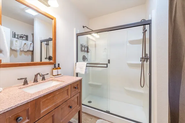 a bathroom with a granite countertop shower sink vanity and mirror