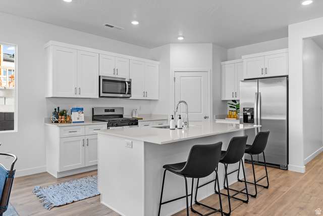 1589 South Fins Road, Unit 4178 Washington, UT 84780 - Photo 13 of 30 Modern kitchen featuring white shaker cabinetry, stainless steel appliances, a center island with countertop seating, recessed lighting, and wood-finish flooring