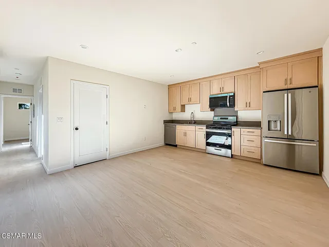 a view of kitchen with stainless steel appliances wooden floor and large window