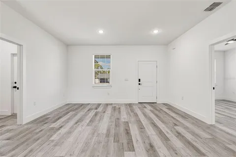 a view of empty room with wooden floor and fan