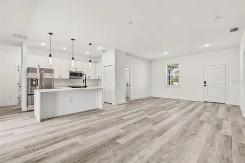 a large white kitchen with kitchen island a sink stainless steel appliances and cabinets