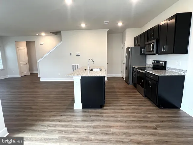 a kitchen with stainless steel appliances granite countertop a stove a sink dishwasher and a refrigerator with wooden floor