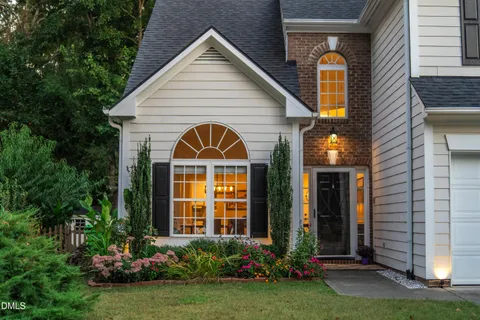 a view of a house with brick walls and a yard with plants
