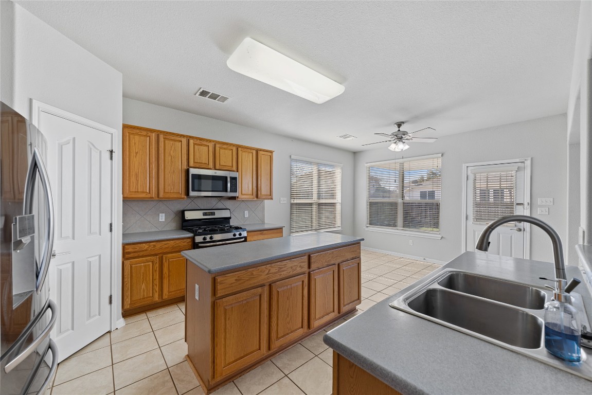 12017 Lansdowne Road Austin, TX 78754 - Photo 7 of 30 a kitchen with granite countertop a stove a sink and a refrigerator