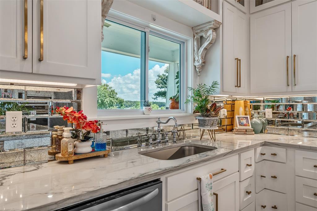 16241 Big Oak Bay Road Tyler, TX 75707 - Photo 10 of 40 White cabinetry with brass hardware, a polished sink, stone countertops, and a mirrored subway tile backsplash