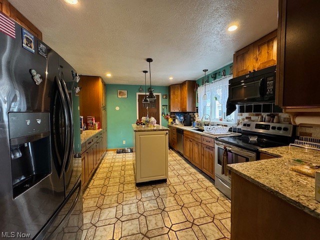 3096 Wayland Road Diamond, OH 44412 - Photo 3 of 26 Kitchen featuring a textured ceiling, black appliances, decorative light fixtures, a kitchen island, and backsplash