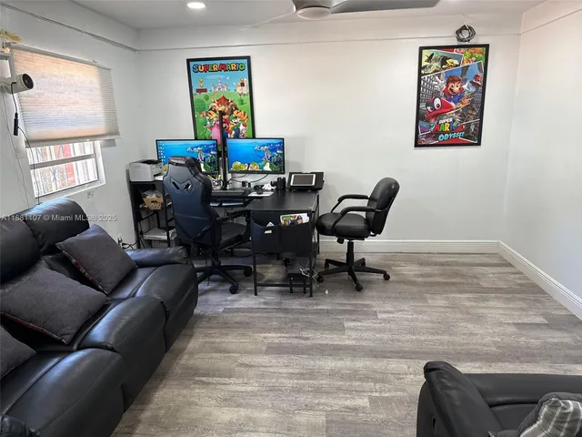 a living room with furniture a computer on the desk and a large window