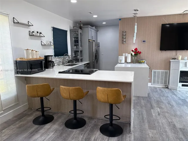 a kitchen with stainless steel appliances kitchen island granite countertop a table chairs and a flat screen tv