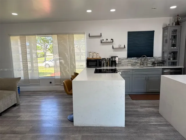 a kitchen with stainless steel appliances granite countertop a stove a sink dishwasher and a microwave with wooden floor