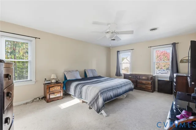 a spacious bedroom with a bed a dresser and a window