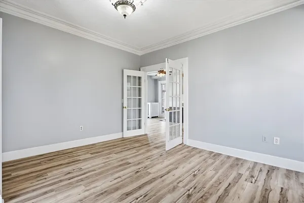 an empty room with wooden floor closet and windows