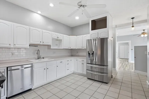 a kitchen with white cabinets and appliances