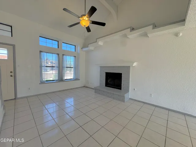 an empty room with windows and chandelier fan