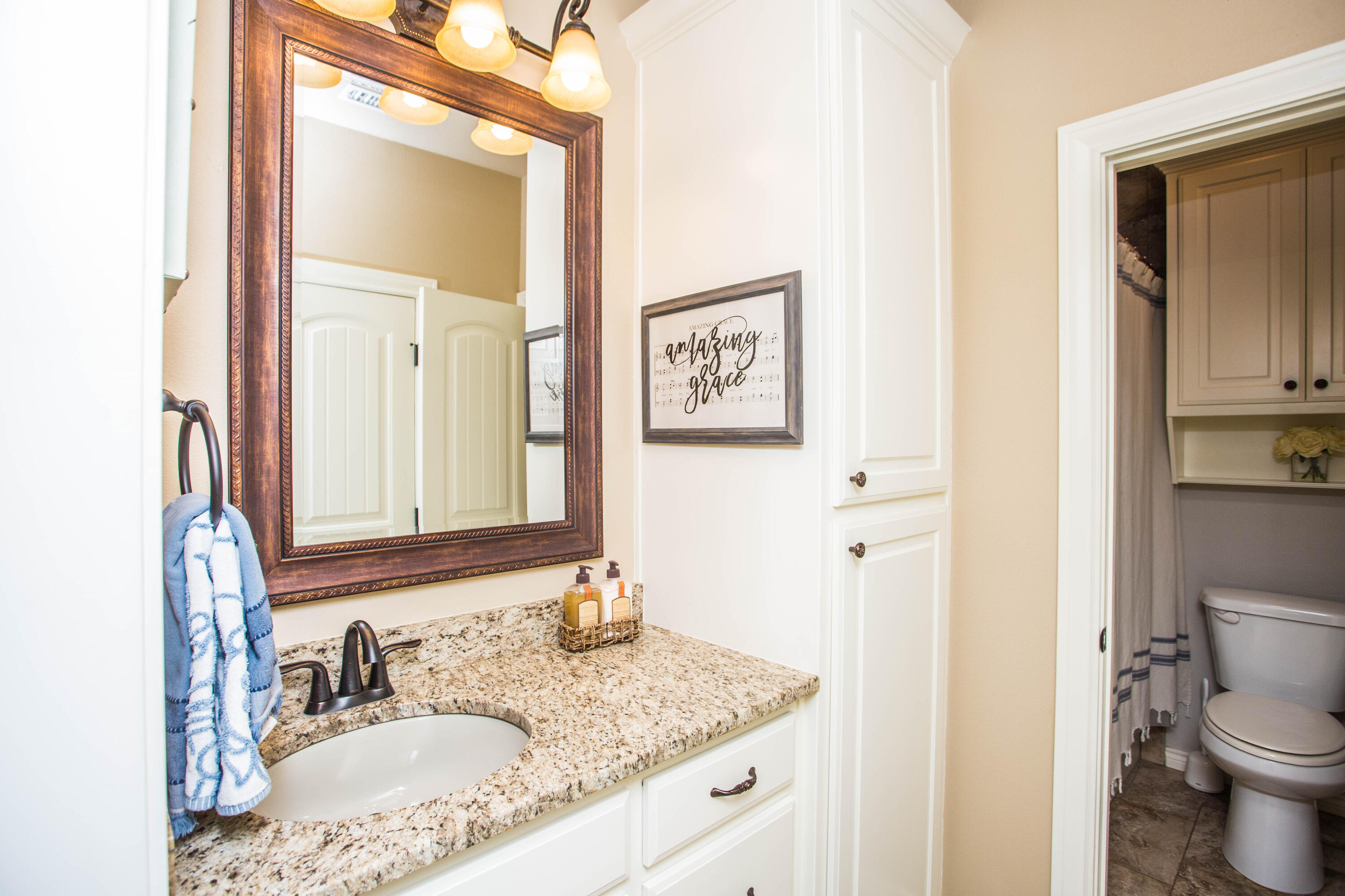 6018 87th Street Lubbock, TX 79424 - Photo 50 of 98 a bathroom with a granite countertop sink toilet and mirror
