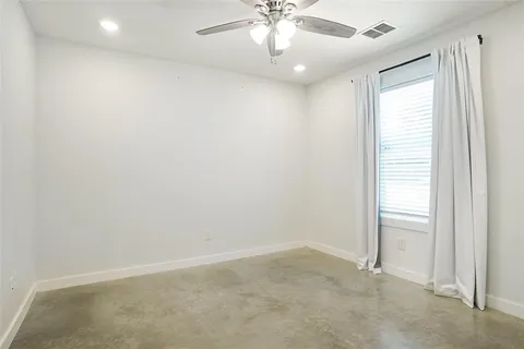 an empty room with a chandelier fan and windows