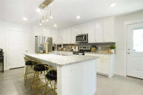 a kitchen with kitchen island granite countertop stainless steel appliances cabinets a sink and a counter top space