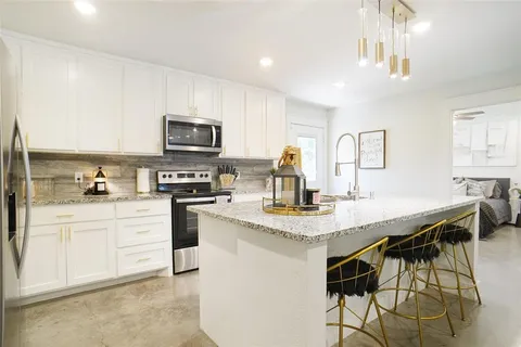 a kitchen with stainless steel appliances granite countertop a stove a sink dishwasher and a refrigerator