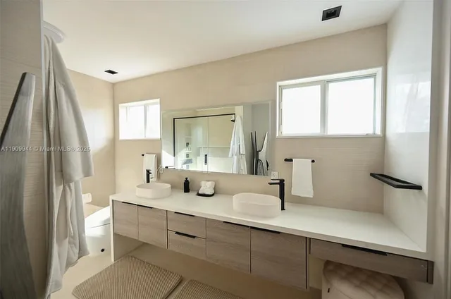 a bathroom with a double vanity sink window and mirror