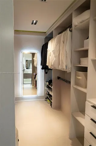 a view of walk in closet with clothes and shoes