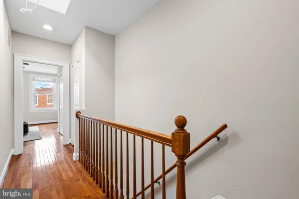 a view of a hallway with wooden floor and a bathroom