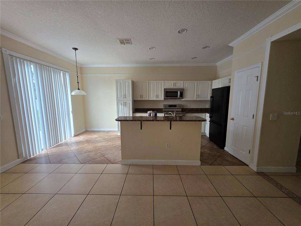 830 Neptune Pointe Lane Kissimmee, FL 34744 - Photo 4 of 10 a kitchen with stainless steel appliances granite countertop a refrigerator sink and cabinets