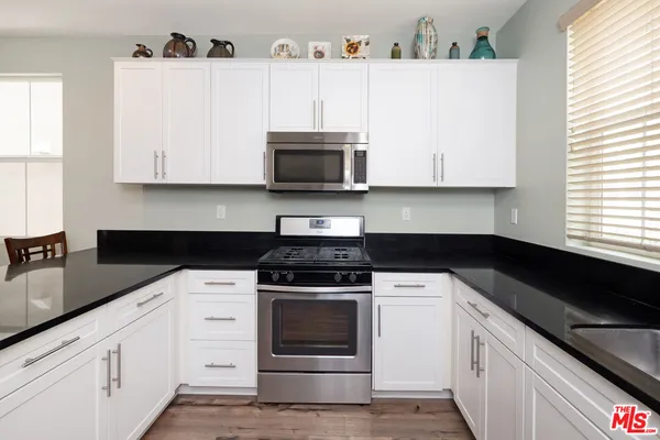 a kitchen with granite countertop white cabinets and black appliances