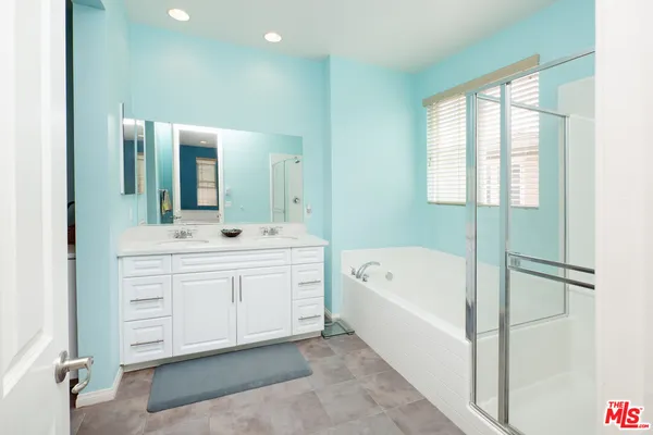 a spacious bathroom with a double vanity sink a mirror and a bathtub