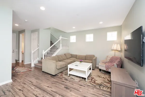 a living room with furniture a flat screen tv and a wooden floor