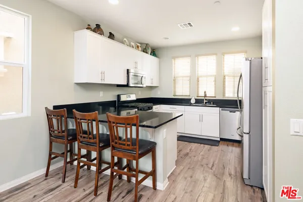 a kitchen with stainless steel appliances granite countertop a table chairs sink and cabinets