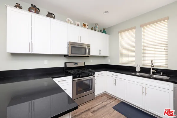 a kitchen with granite countertop white cabinets and white appliances