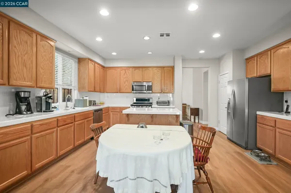 a kitchen with stainless steel appliances granite countertop a refrigerator a stove top oven a sink dishwasher and white cabinets with wooden floor