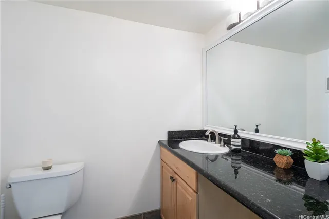 a bathroom with a granite countertop sink and a toilet