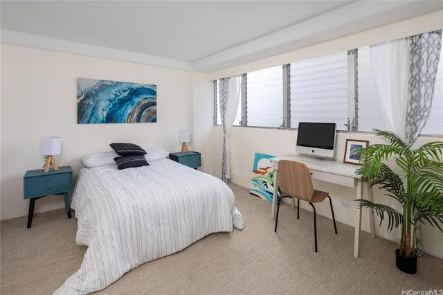 a bedroom with a bed a computer on the desk and a potted plant