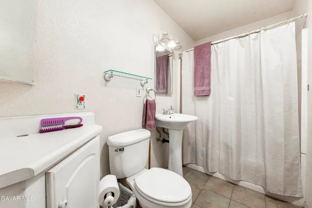 a bathroom with a sink a toilet and shower curtain