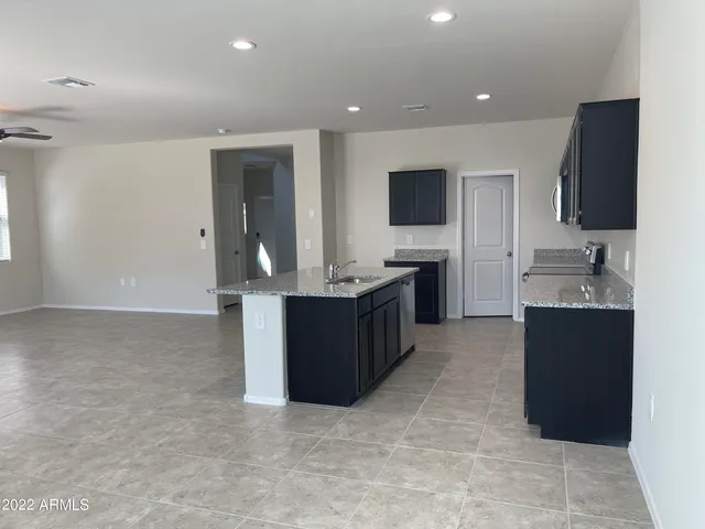 a living room with stainless steel appliances kitchen island granite countertop a sink and cabinets