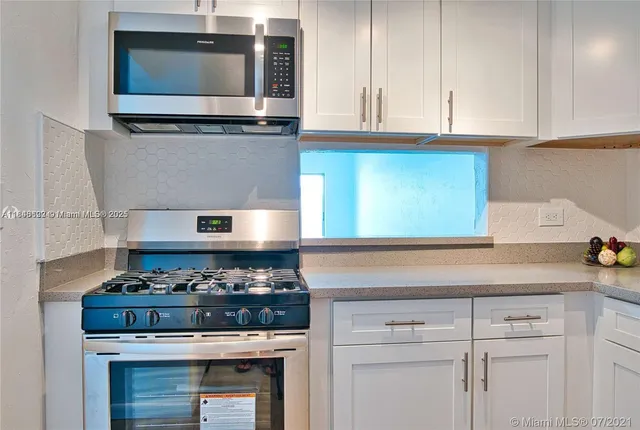 a kitchen with stainless steel appliances granite countertop white cabinets and a stove top oven