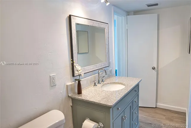 a bathroom with a granite countertop sink a toilet and mirror