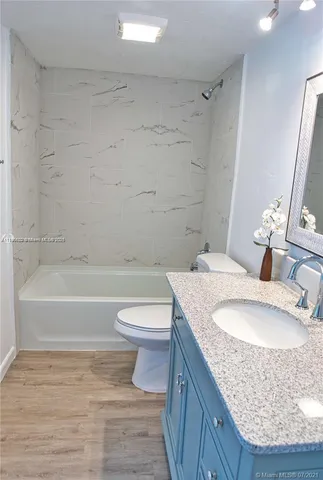 a bathroom with a granite countertop bathtub sink vanity mirror and toilet