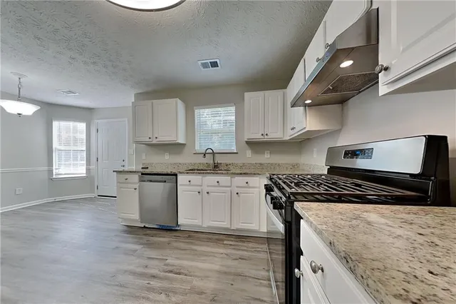 a kitchen with granite countertop a stove top oven a sink a counter space and cabinets