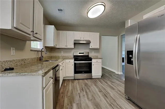 a kitchen with granite countertop a refrigerator stove and sink
