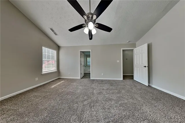 a view of an empty room with window and a ceiling fan