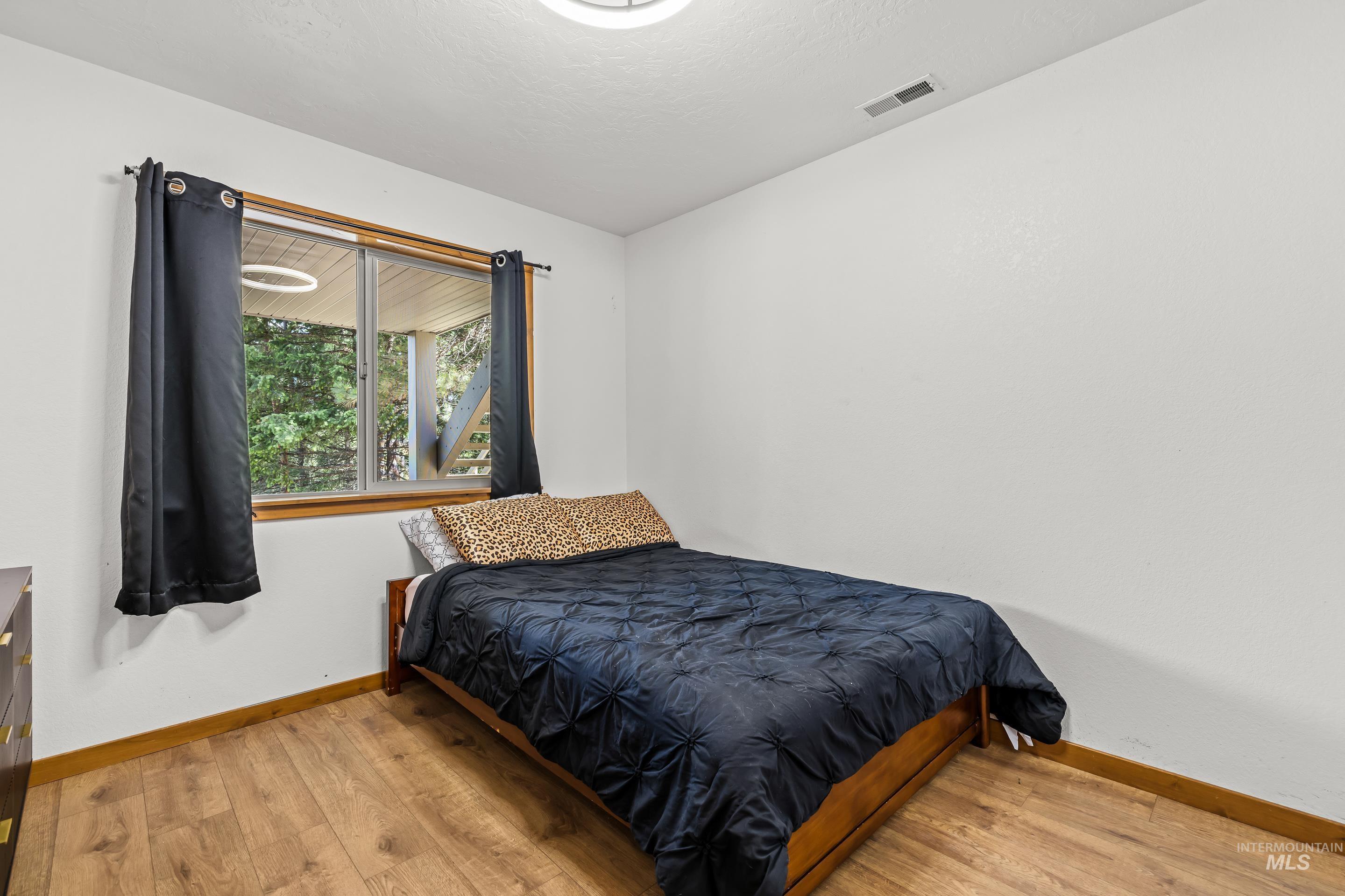 92 Cruickshank Road Horseshoe Bend, ID 83629 - Photo 32 of 50 Bright room featuring a large window, wood-finish flooring, white walls, and a ceiling-mounted light fixture