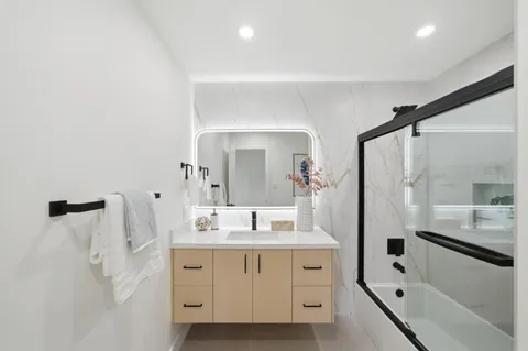 a bathroom with a double vanity sink a mirror a bathtub and shower