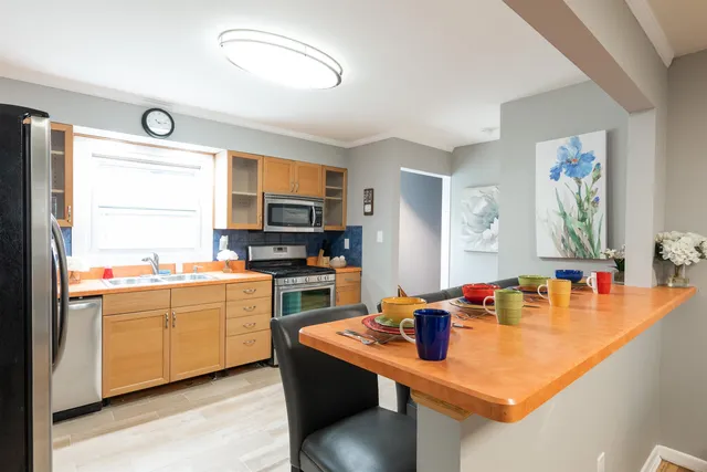 a room with stainless steel appliances kitchen island granite countertop a sink and a refrigerator