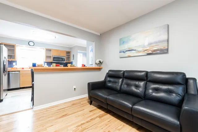 a living room with stainless steel appliances furniture and a kitchen view